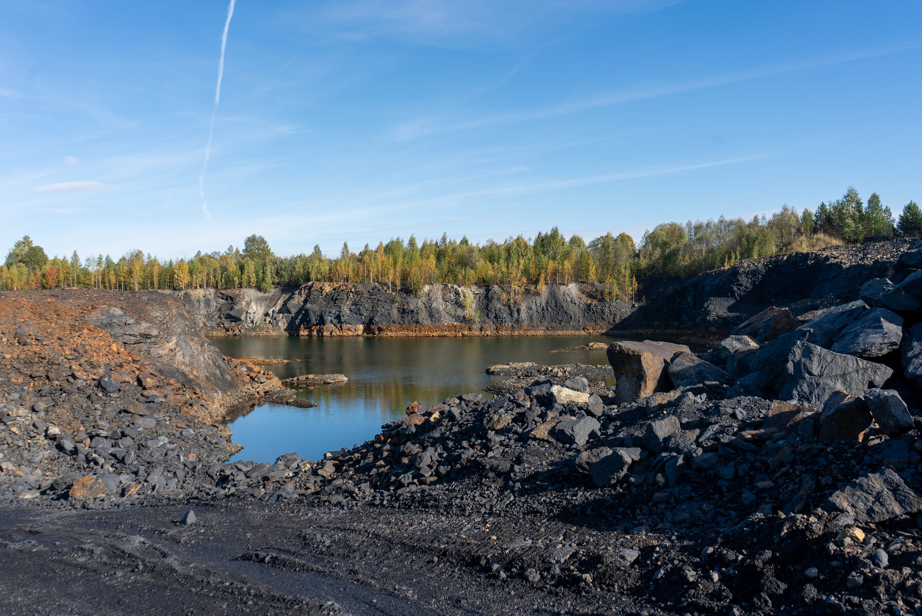 Offene Steinbruchlandschaft mit dunklem Mineralgestein